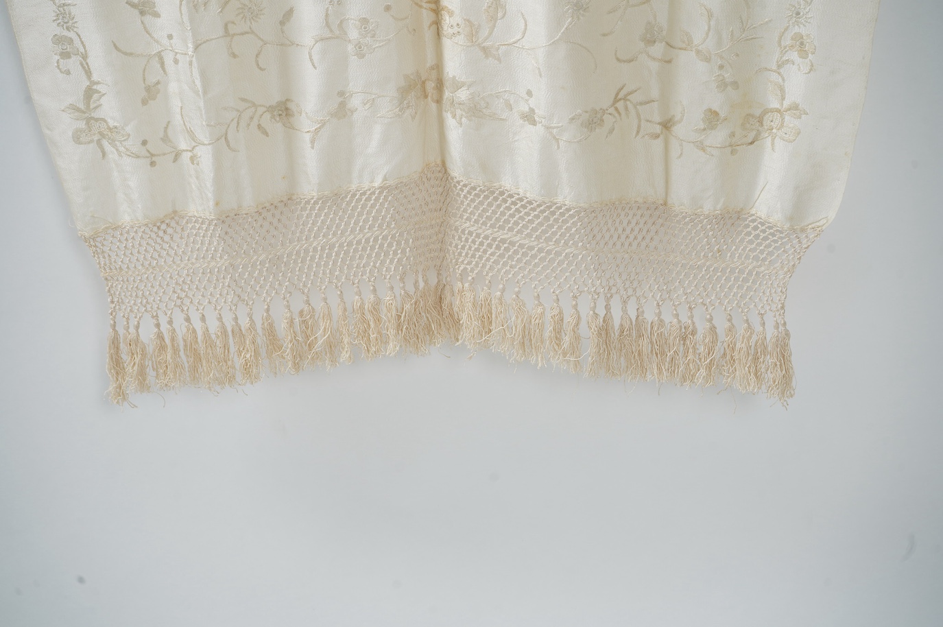 An early 20th century Chinese cream on cream silk embroidered, fringed stole, 65cm wide. Condition - some light staining.